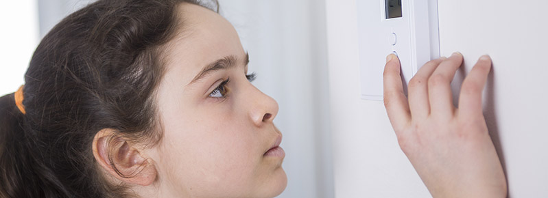 Girl adjusting thermostat