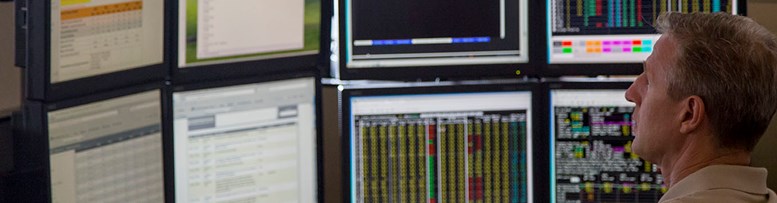 Energy Marketing employee monitoring eight computer screens containing data